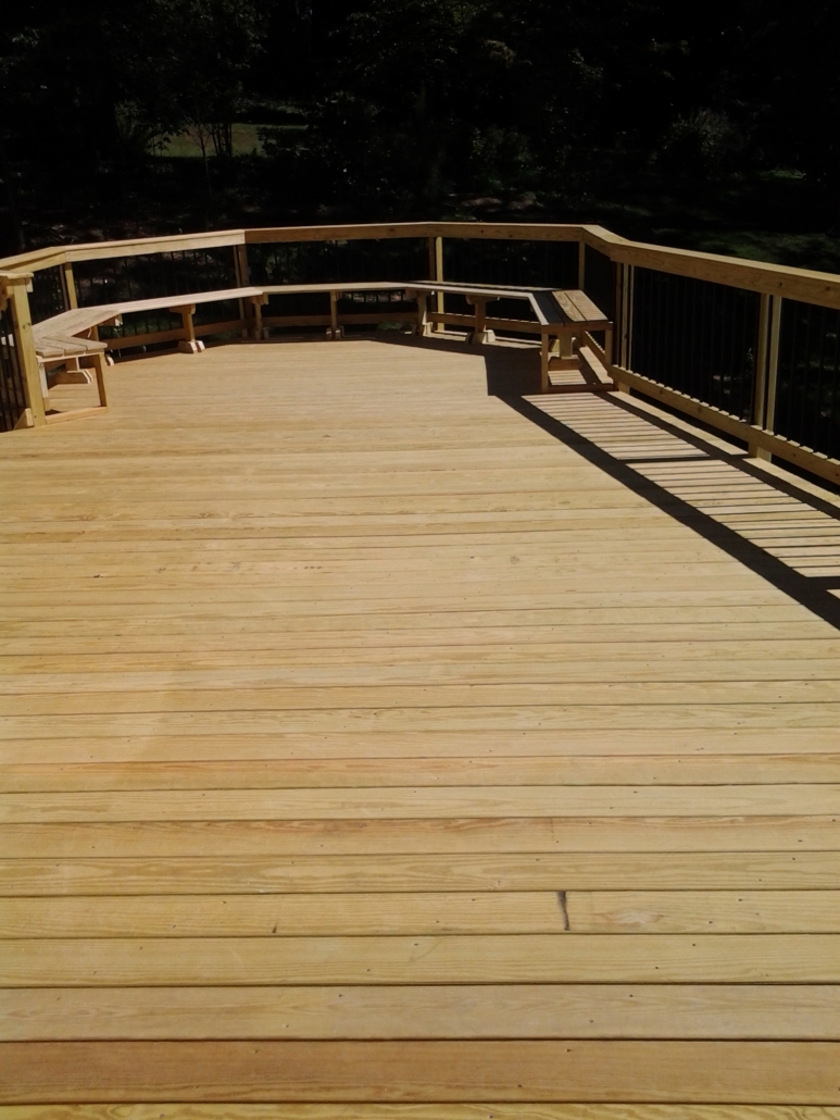 Finished new wood deck with railings in a wooded backyard