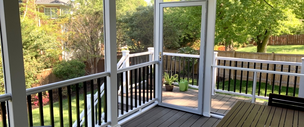 Covered porch and composite deck with white railings overlooking a green backyard