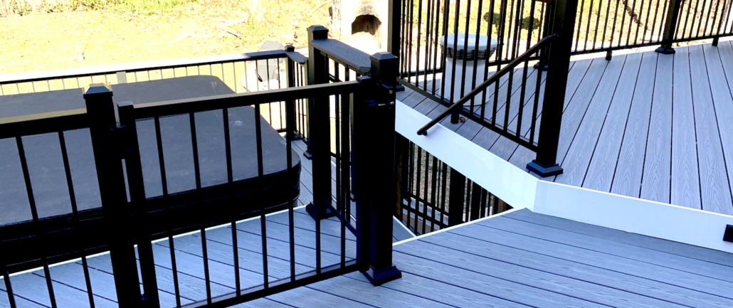 Composite deck with black aluminum railings and stairs leading down to a lawn