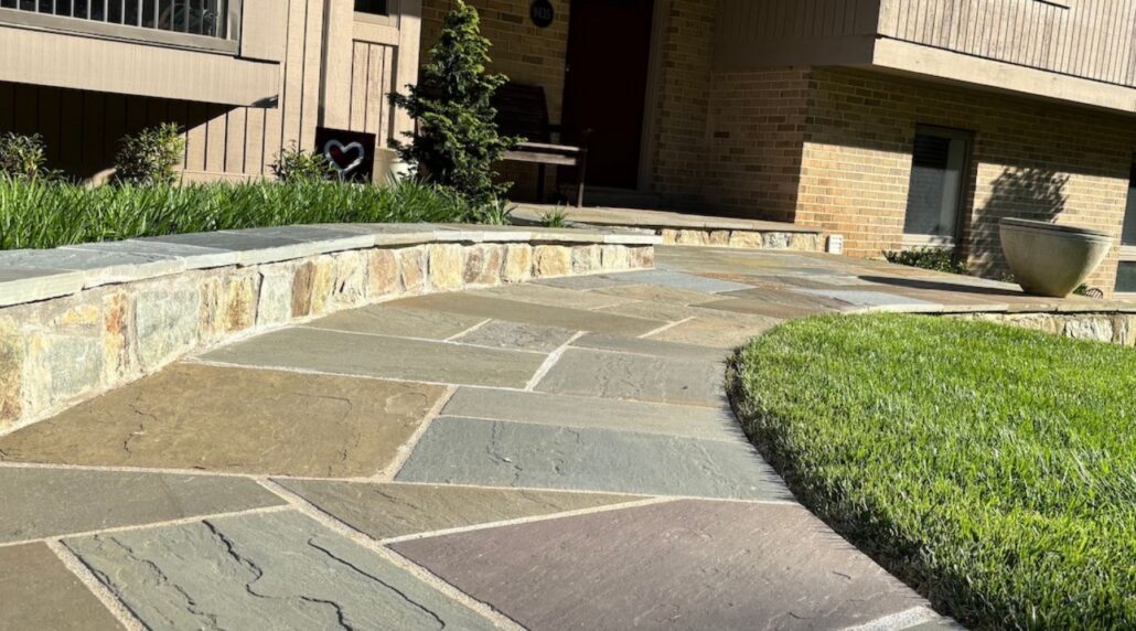 Flagstone patio with a curved stone seating wall beside a green lawn